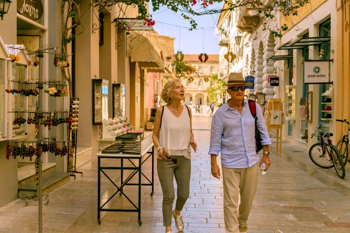  two people walk along a pretty street in Nafplion looking at the local shops