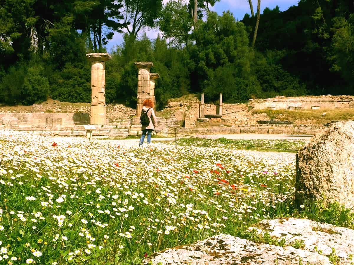 a visitor looks at the ruins of the temple of zeus at ancient olympia