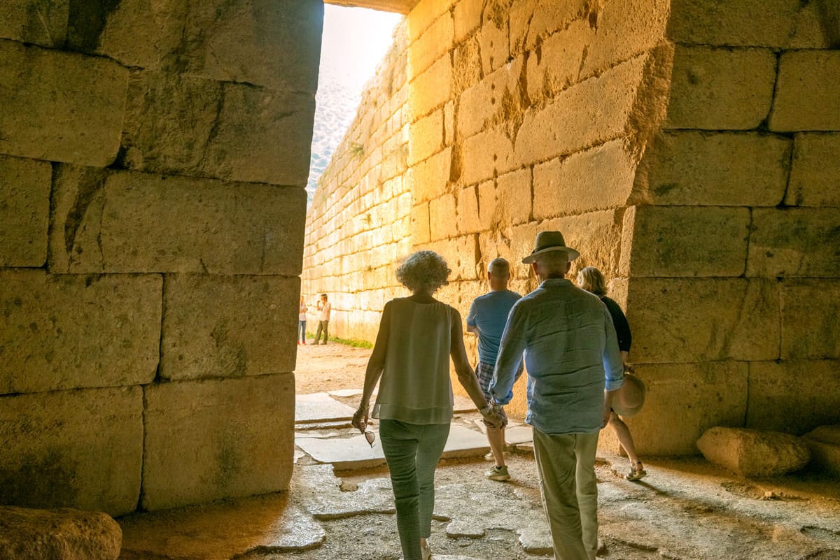 two tourists enter a tomb in mycenae during their visit