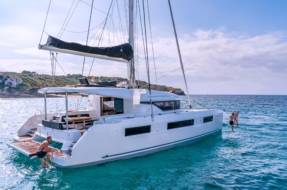 a family group jump into the sea from a luxury catamaran